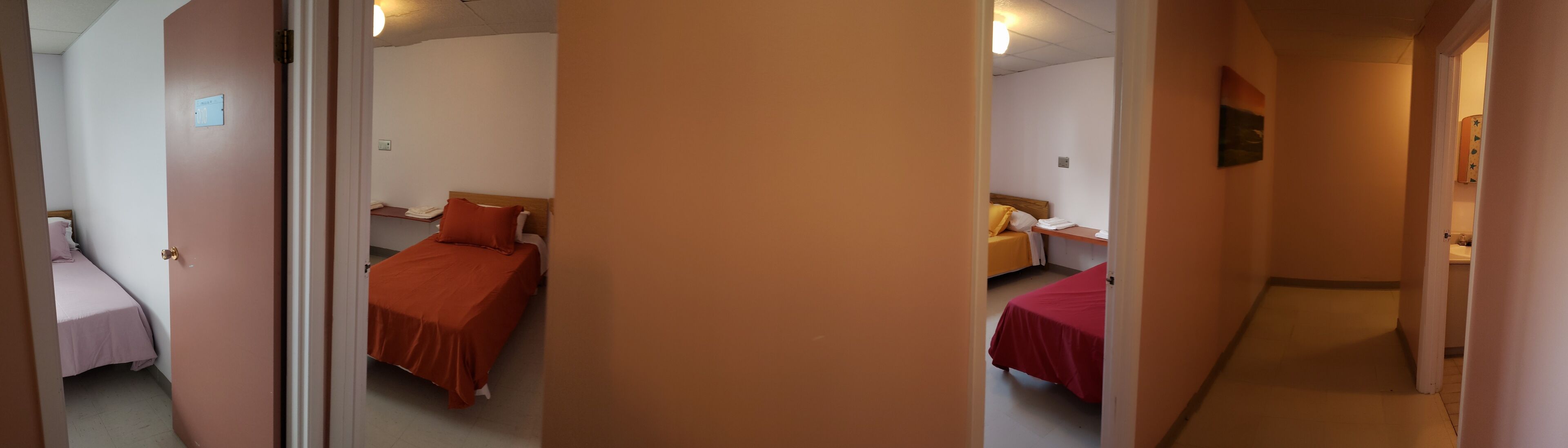 A corridor leading to three bedrooms, each with a bed and a bedside table.