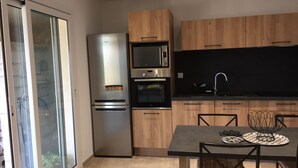 Eine moderne Küche mit integriertem Kühlschrank, Backofen, Mikrowelle und einem Essbereich mit Tisch und Stühlen.