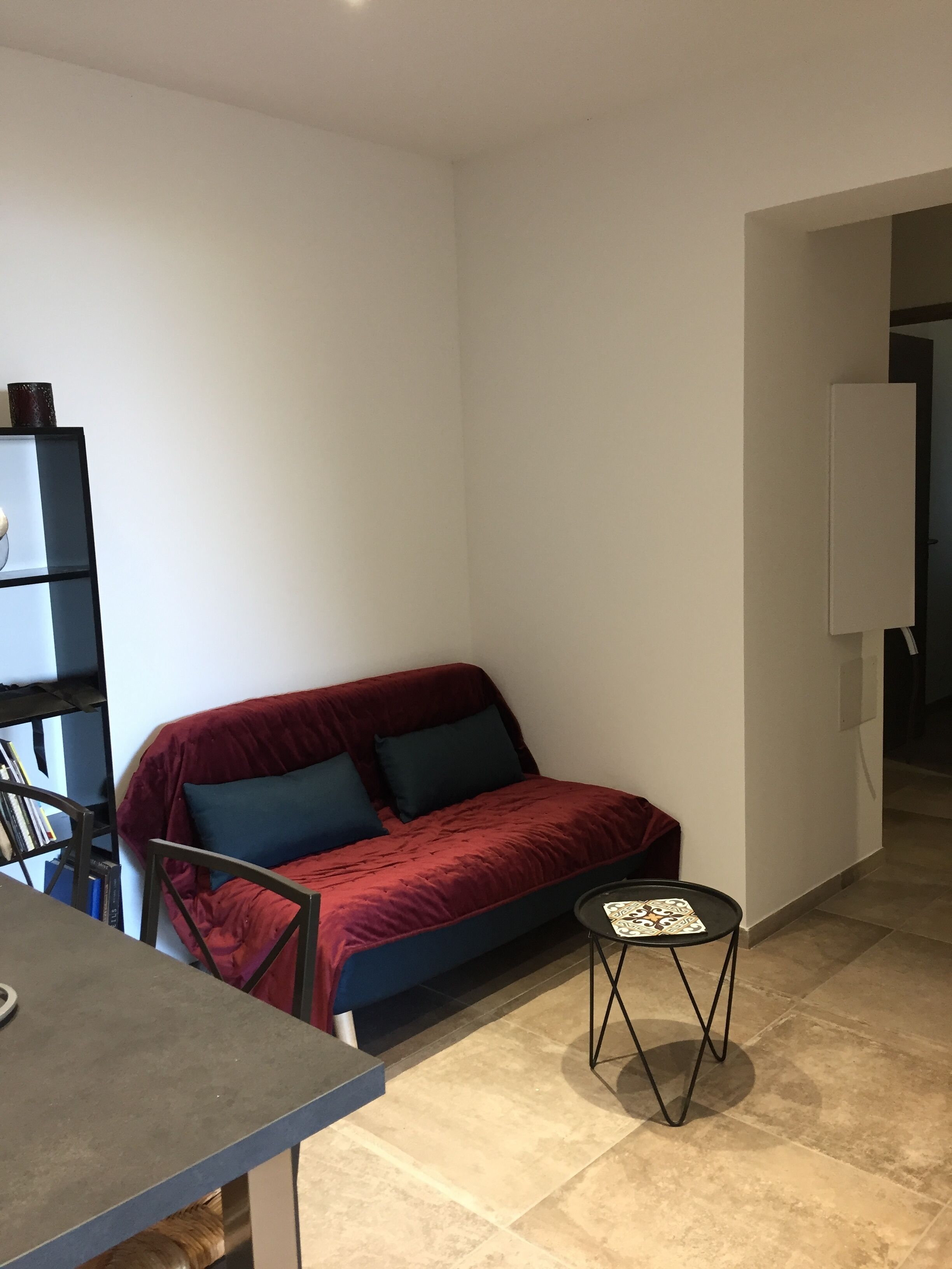 A compact living space with a red sofa, a small round table, and a bookshelf.