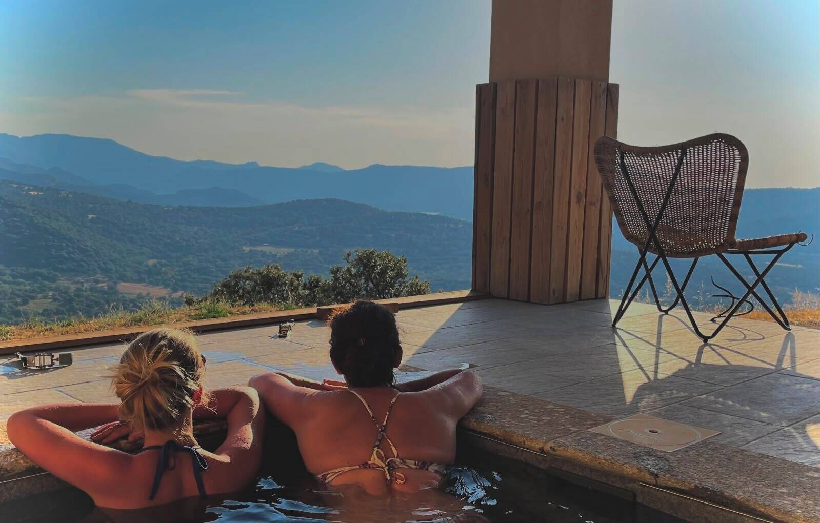 Ein Paar entspannt am Pool mit Blick auf die Berge.