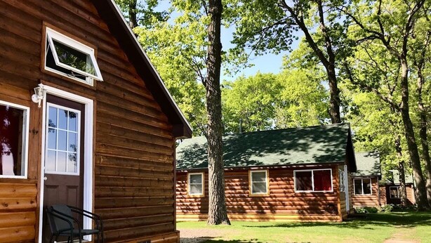 A wooden cabin with a porch, a small table, and a chair.