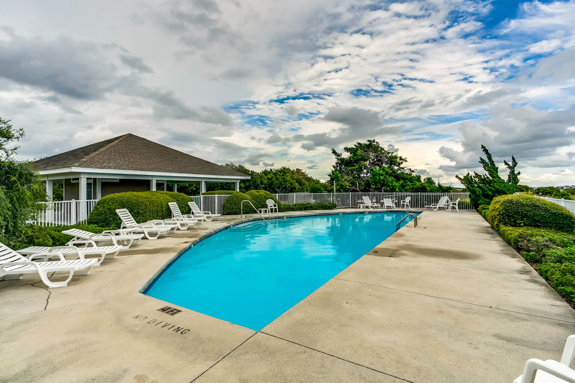 A swimming pool with lounge chairs, a covered pavilion, and a 'No Diving' sign.