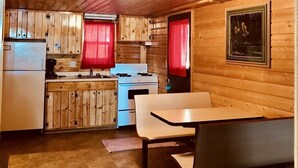 A compact kitchen with wooden cabinets, a white stove, and a bench.