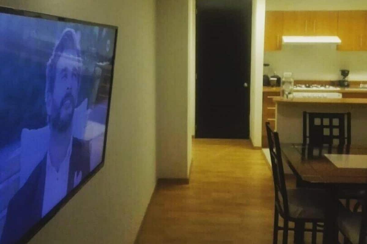 A modern kitchen with wooden cabinets, a built-in oven, and a dining area with a table and chairs.