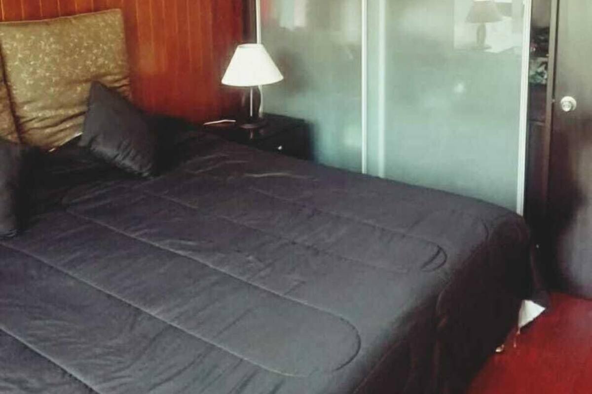 A bedroom with a bed, a nightstand, a lamp, and a sliding glass door.