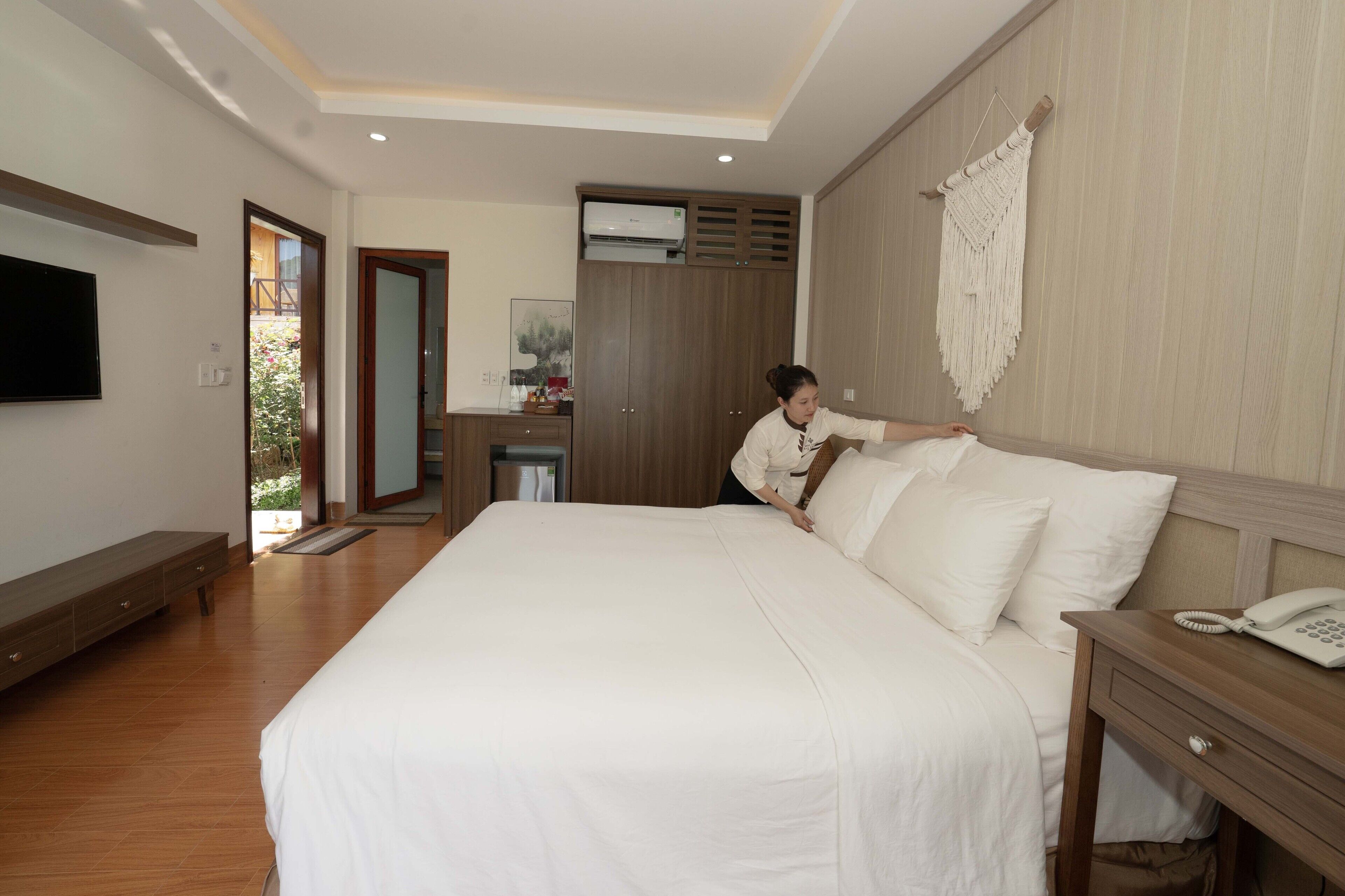 Een ruime slaapkamer met een groot bed, een houten garderobe en een bedtelefoon.
