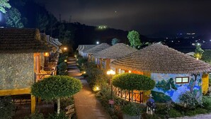 Una hilera de edificios de estilo tradicional con techos de paja, un sendero pavimentado y un mural en una de las construcciones.