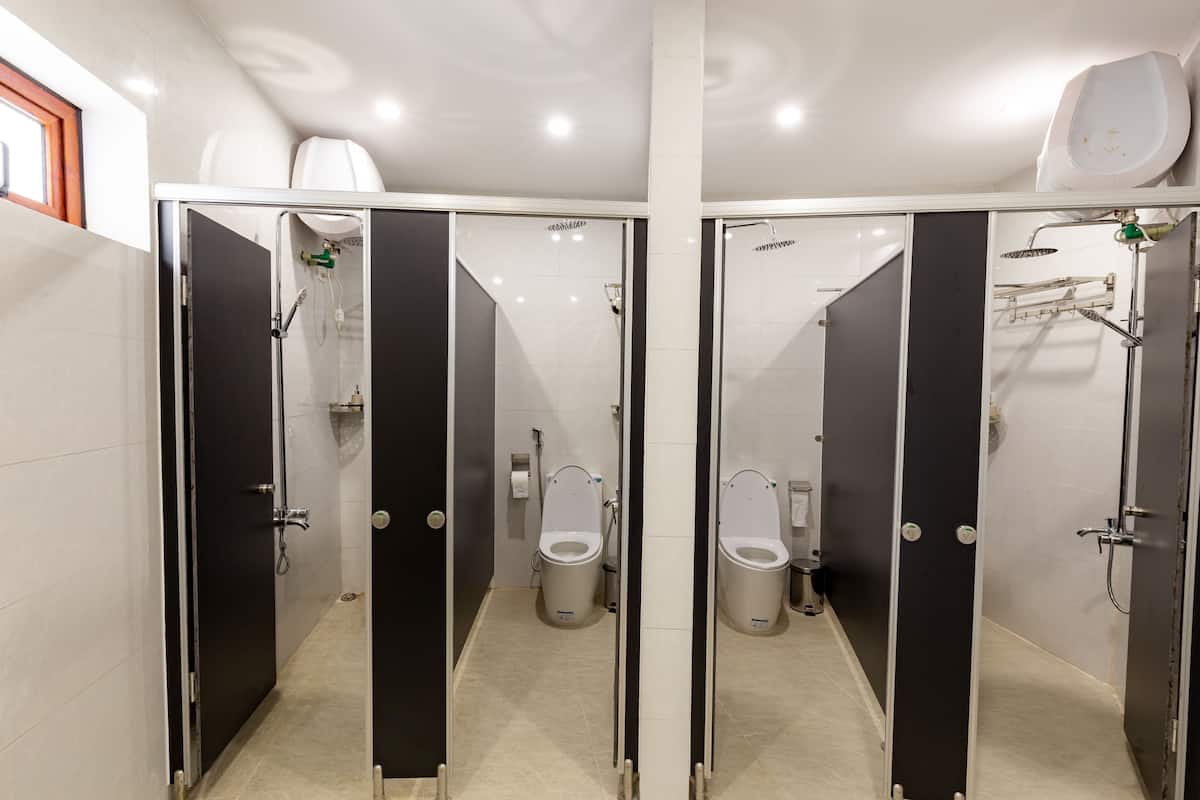 Ein modernes Badezimmer mit zwei separaten Kabinen, jeweils ausgestattet mit einer Toilette, einem Händetrockner und einem Papierhandtuchspender.