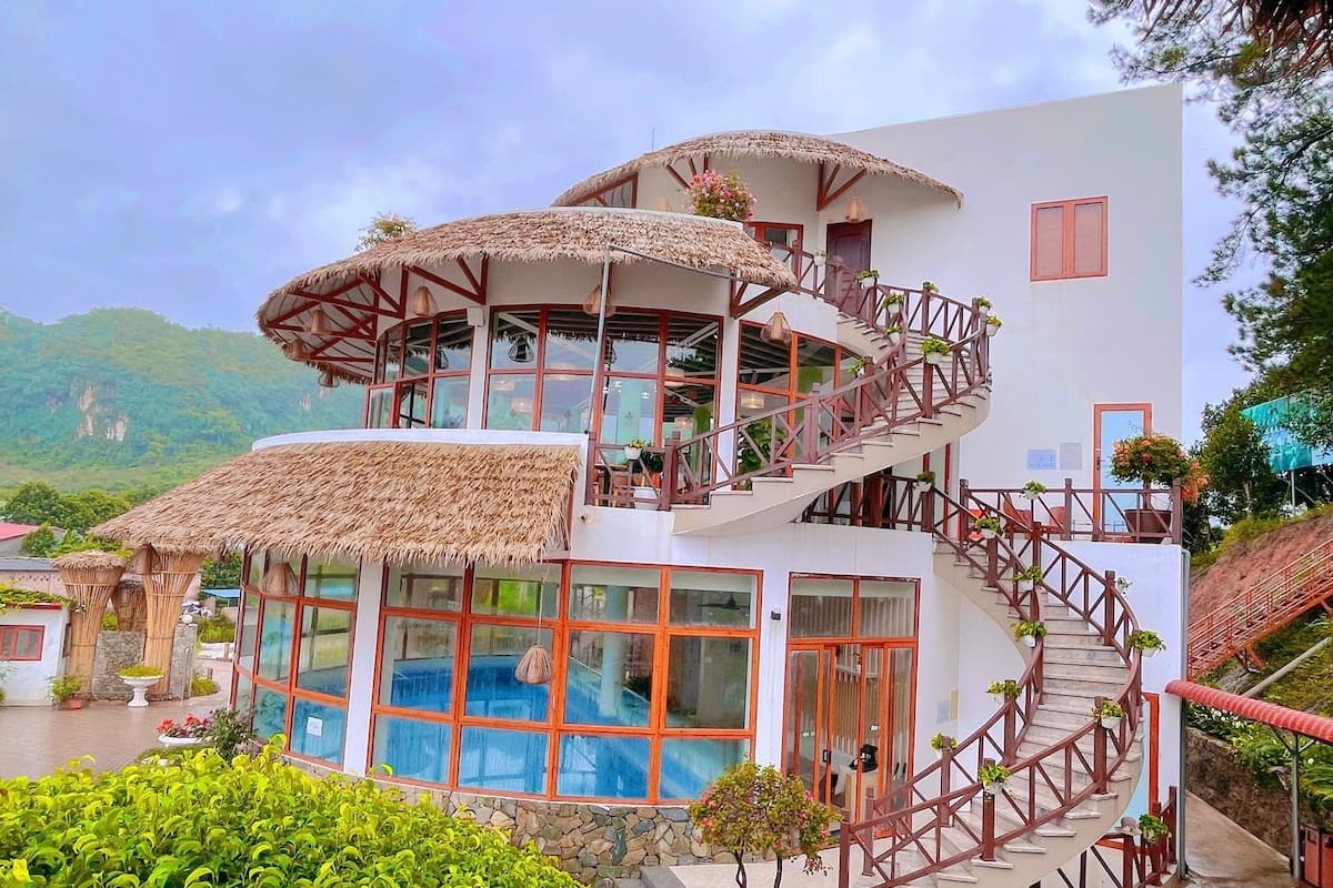 Ein mehrstöckiges Gebäude mit einer Wendeltreppe, großen Fenstern und einem Poolbereich.