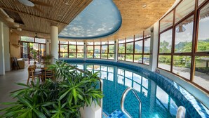 Una piscina con techo curvo y amplios ventanales que dan a zonas verdes.