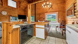 A log cabin interior with a kitchen, dining area, and a view of the outdoors. - Spacious Beautiful Log Cabin Accessible Year Round (Scofield)