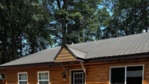 A log cabin with a deck, outdoor seating, and a large window.