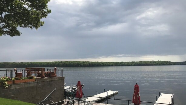 A lakeside dock with a seating area, a boat, and a view of the lake.