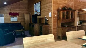 A wooden interior with a sofa, a television, and a dining area with benches.
