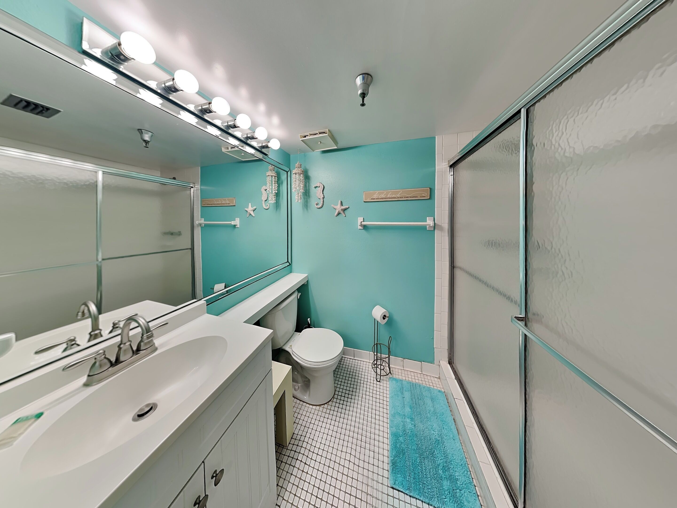 Ein Badezimmer mit einem weißen Waschbecken, einer Toilette und einer Duschkabine aus Glas.