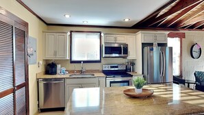 A modern kitchen with white cabinets, stainless steel appliances, and a granite countertop. - Seashell by Distinctive Beach Rentals (Ponte Vedra Beach)