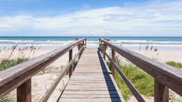 A wooden boardwalk leading to a beach with waves in the background. - Seashell by Distinctive Beach Rentals (Ponte Vedra Beach)