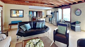 A spacious living area with a black leather sofa, a dining table, and a kitchen in the background. - Seashell by Distinctive Beach Rentals (Ponte Vedra Beach)