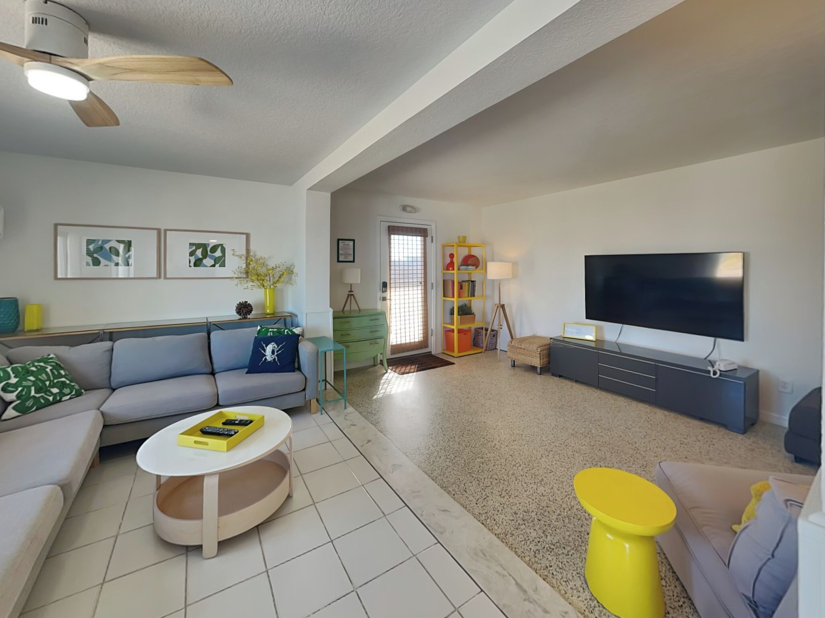 Ein modernes Wohnzimmer mit Sofa, Couchtisch, Fernseher und Deckenventilator.