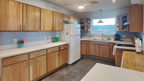 Cocina moderna con armarios de madera, un refrigerador blanco y un ventanal con vistas.