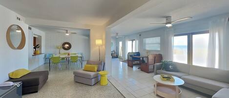 A spacious living area with a dining table, chairs, sofas, and a coffee table.