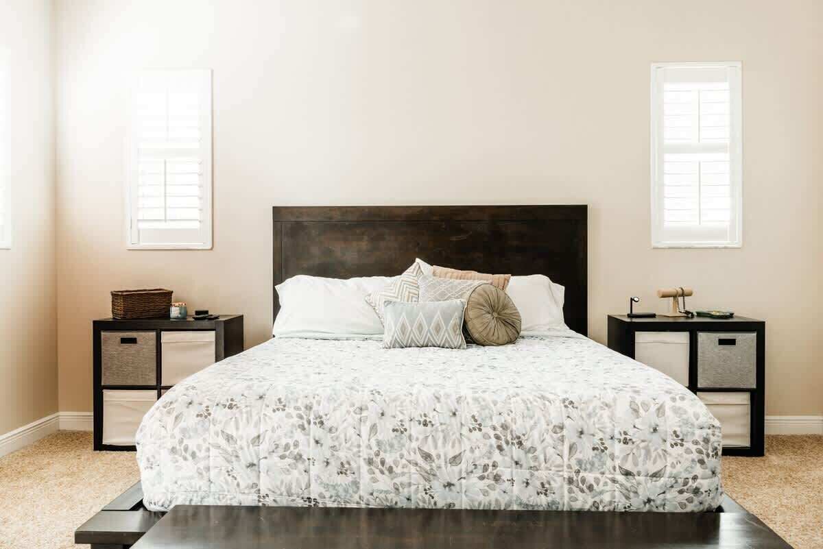 A bedroom with a large bed, two nightstands, and a window with shutters.