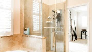 A modern bathroom with a glass-enclosed shower, a freestanding bathtub, and a vanity with a mirror.