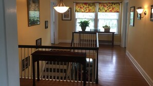 A hallway with a staircase, a dining area with a table and chairs, and a window with floral curtains. - 3 Bedroom Home in the Highlands, close to everything (Louisville)