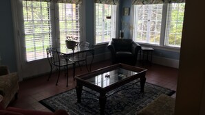 A living room with a glass coffee table, a black leather chair, a dining table with chairs, and large windows with blinds. - 3 Bedroom Home in the Highlands, close to everything (Louisville)