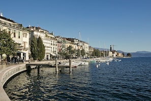 Une promenade en bord de mer, bordée d’immeubles, avec un quai et des bateaux.