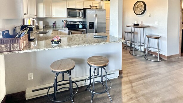 Una cocina moderna con armarios blancos, una isla central con taburetes, un microondas y un refrigerador.