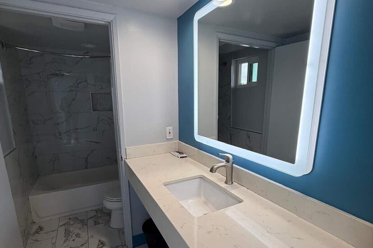 A bathroom with two sinks, a large mirror, and a shower area.