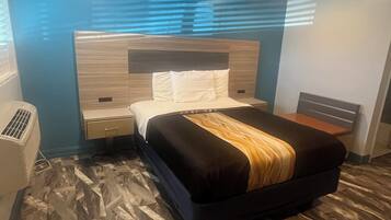Habitació d'hotel amb un llit, una tauleta de nit i un calefactor fixat a la paret.