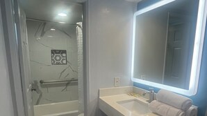 Ein Badezimmer mit Badewanne, Waschbecken mit Spiegel und Duschbereich.