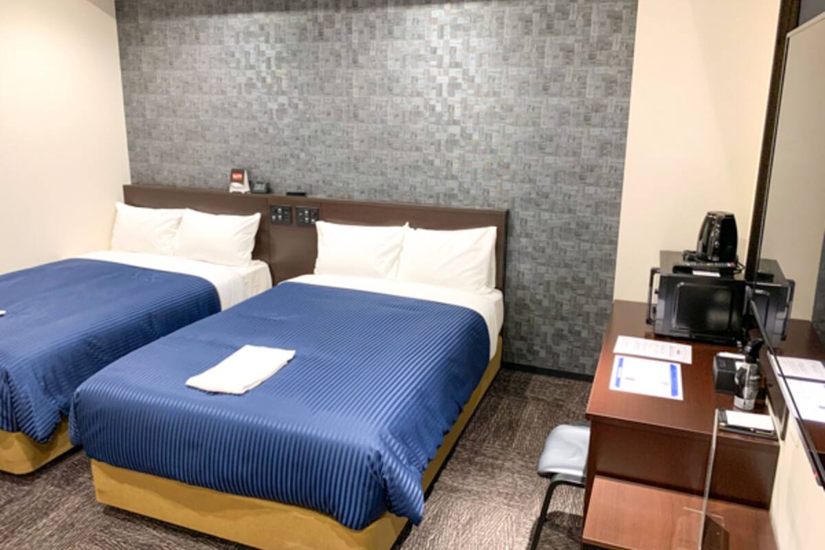 Habitació d'hotel amb dos llits, una taula i una cadira.
