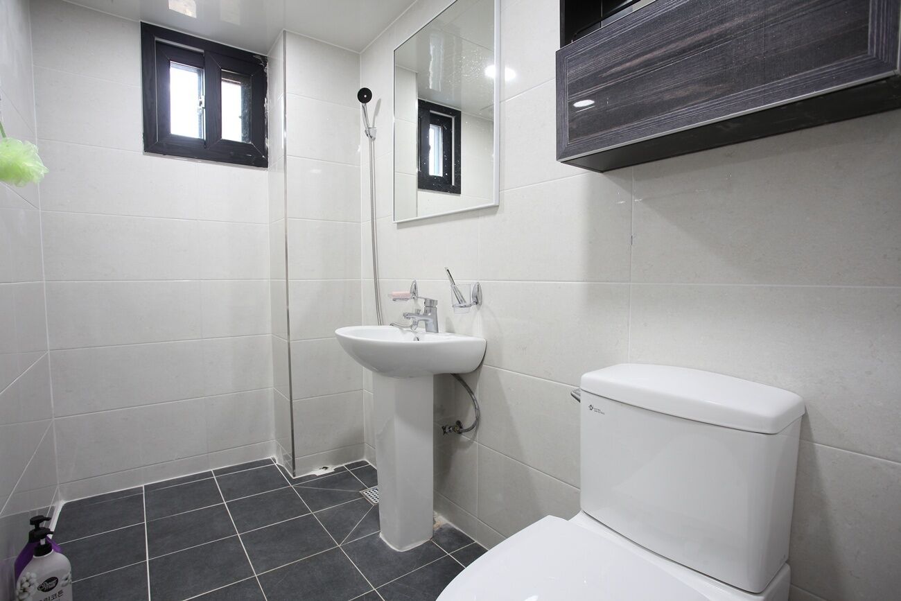 A modern bathroom with a white sink, a toilet, and a shower.