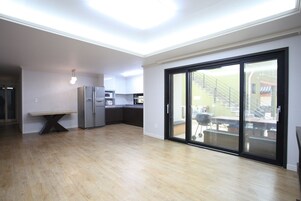 Una cocina amplia con electrodomésticos modernos, un comedor con banco y un ventanal corredero que da a un balcón.