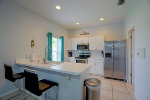 A modern kitchen with a central island, stainless steel appliances, and a view to the outside.