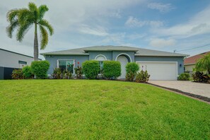 A residential house with a front lawn, a palm tree, and a garage.