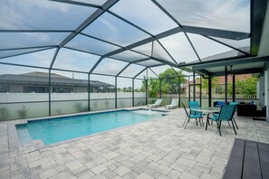 Una piscina exterior techada con sillas de descanso y una mesa.