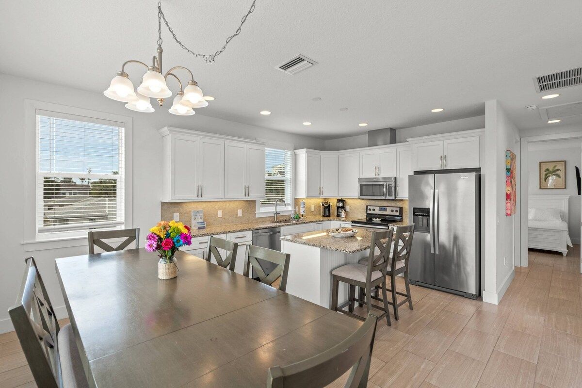 A modern kitchen with white cabinets, stainless steel appliances, and a central island with seating.