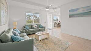 Ein modernes Wohnzimmer mit einer grauen Sofagarnitur, einem Couchtisch und einem Deckenventilator.