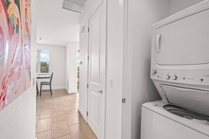 Een wasserette met een wasmachine, een stoel en een deur naar een andere kamer.