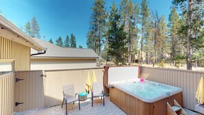 En trädgård med en bubbelpool, två stolar och ett trädäck.