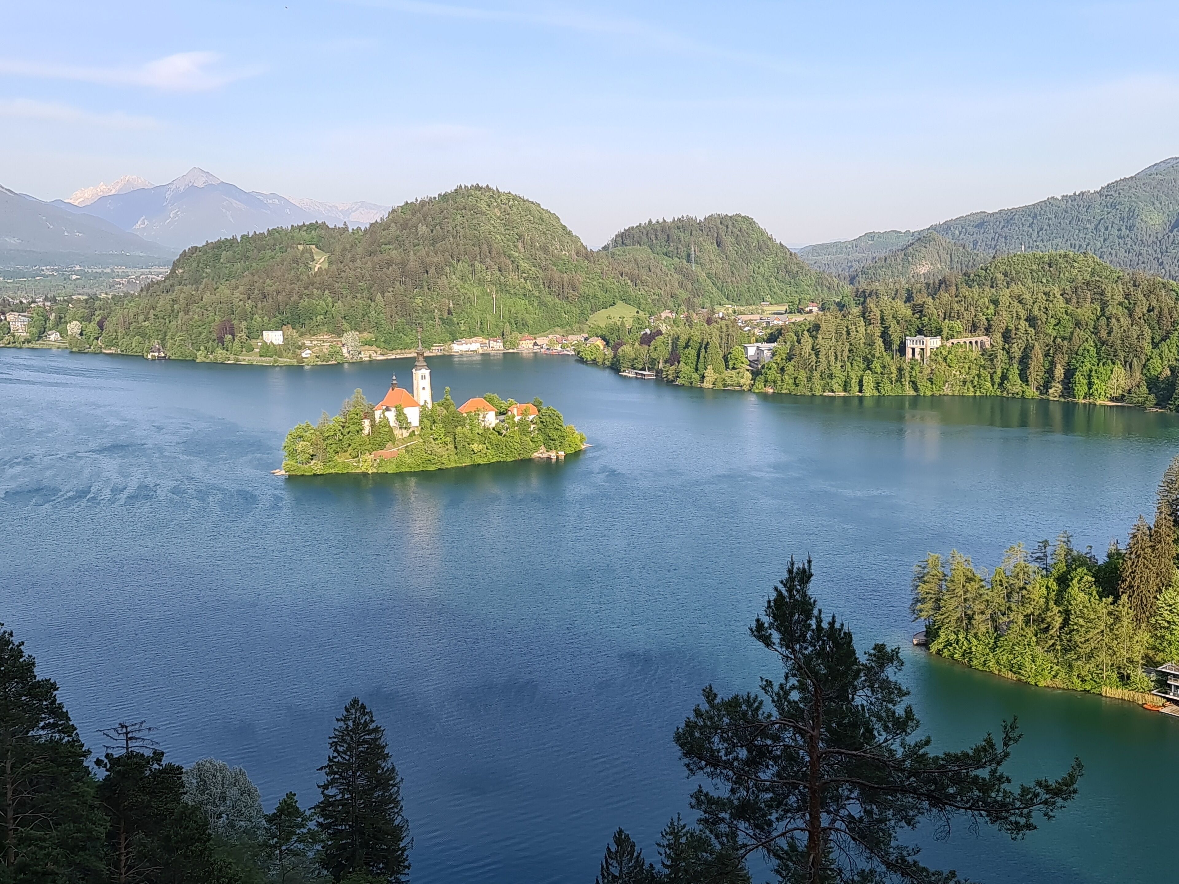 A serene lake with a small island featuring a church and residential buildings.