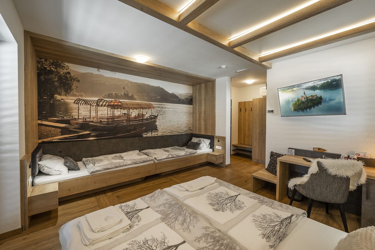 A modern room with a wooden bed, a built-in bench with a scenic mural, a desk with a chair, and a large window.