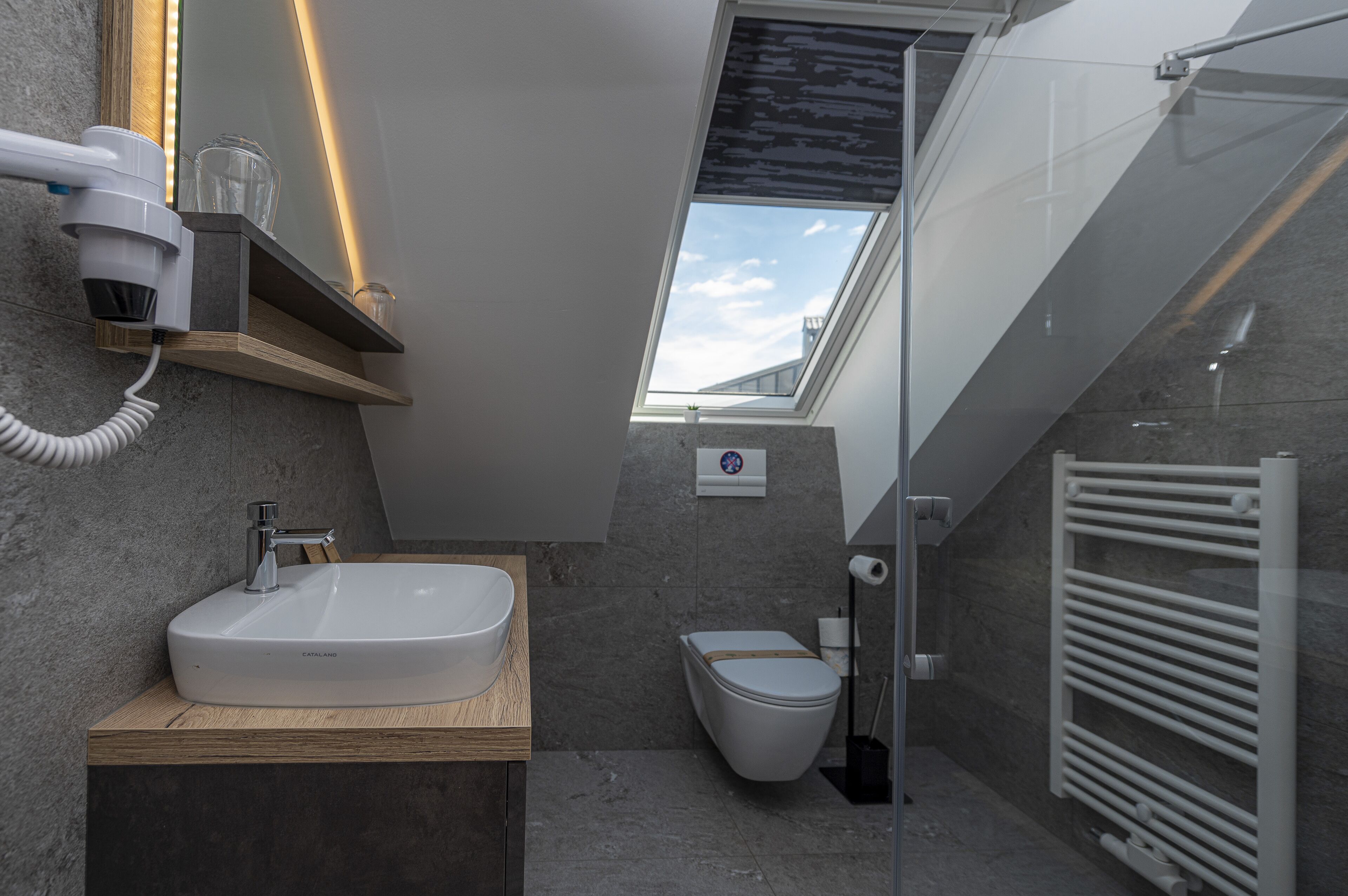 Ein modernes Badezimmer mit Oberlicht, einem weißen Waschbecken und einer Toilette.