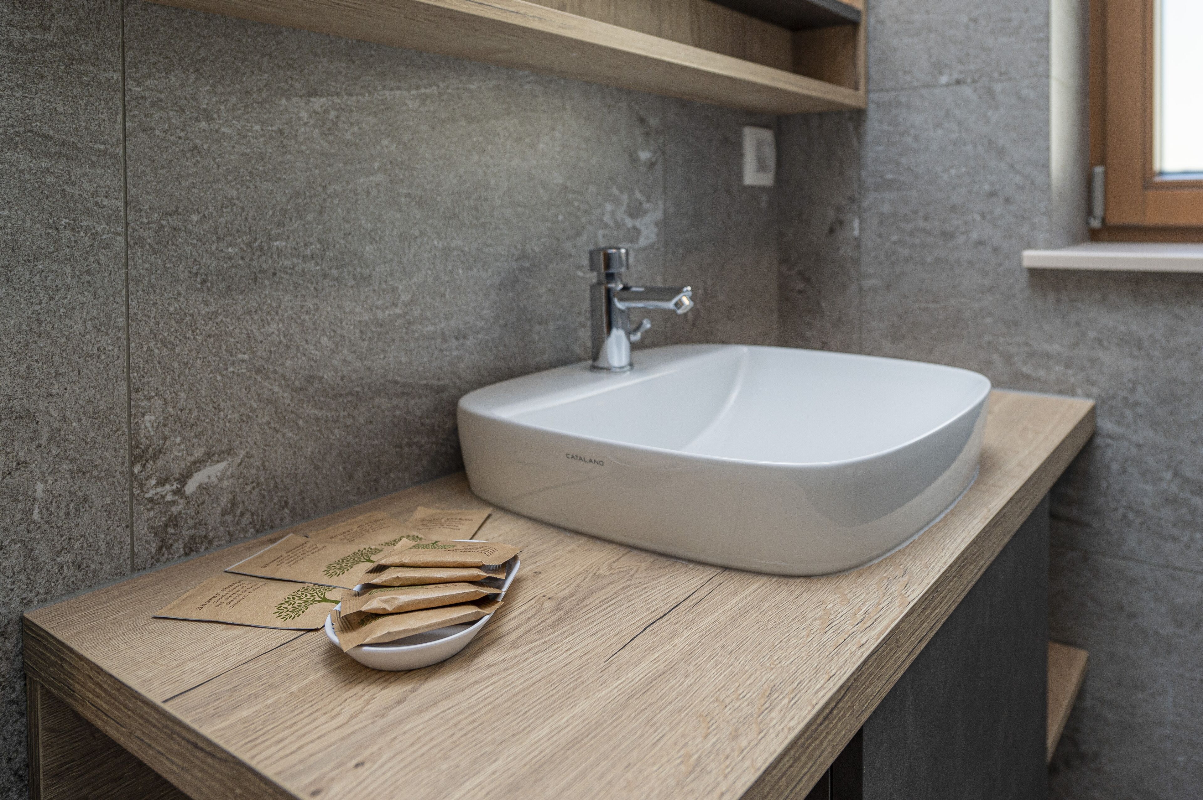 A bathroom with a white sink, wooden countertop, and a towel rack above the sink.