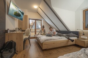 Un dormitorio con cama, escritorio, televisor y ventana con persianas.