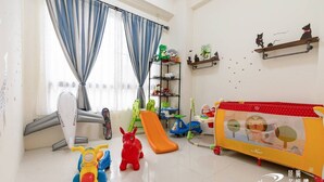 A spacious room with a large window, a play area with toys and a slide, and a colorful playpen. - Wild Fun Hualien (Ji'an)